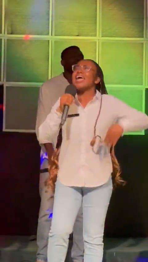 Video: a singer in a white shirt leads a praise song, dancing as she sings.