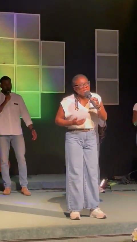 Video: a singer leads worship on a stage lit green, a second singer beside her.