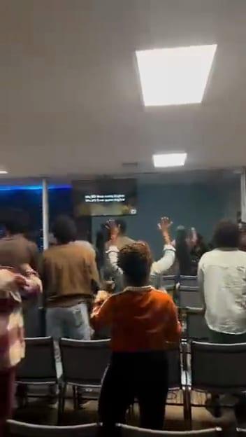 Video: people in the room lift their hands during worship.